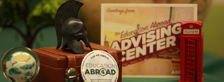 Photo of international souvenirs on a desk with Advising Center Contact info