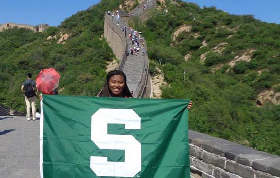 Student holding Spartan flag on Great Wall of China