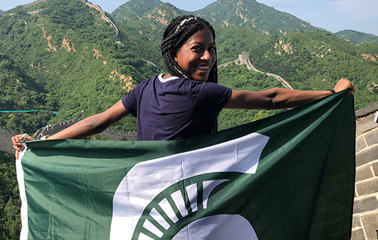 Student standing on Great Wall of China with Spartan flag