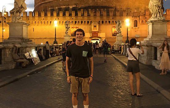 Student standing in front of the Roman capital at night in Rome, Italy