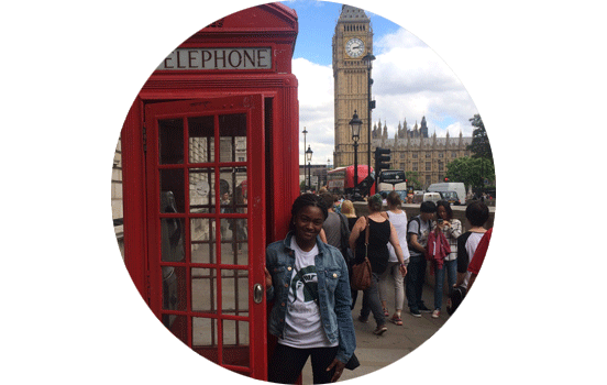 Student standing in red telephone booth in London, England