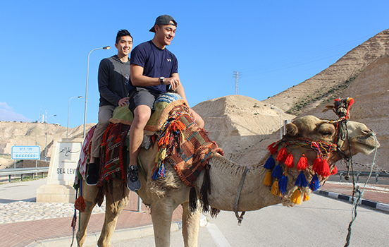 Two students riding a camel in Israel