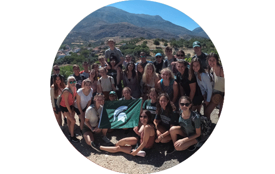 Group of students posing in South Africa holding up Spartan flag