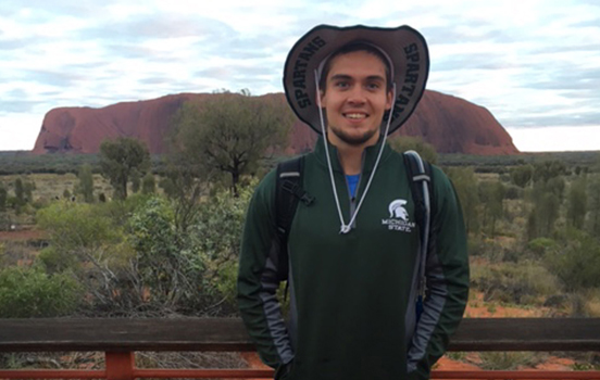 Student standing in front of Ayers Rock in Australia
